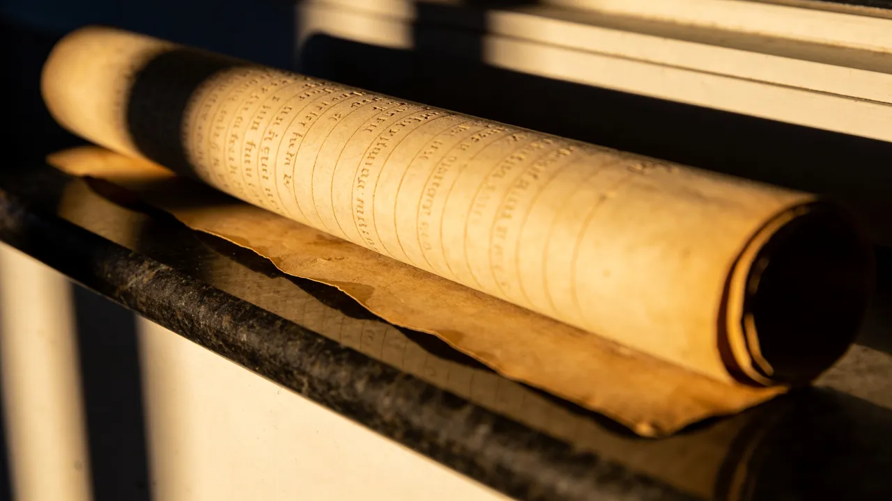 A written scroll resting on a marble sill in low sun